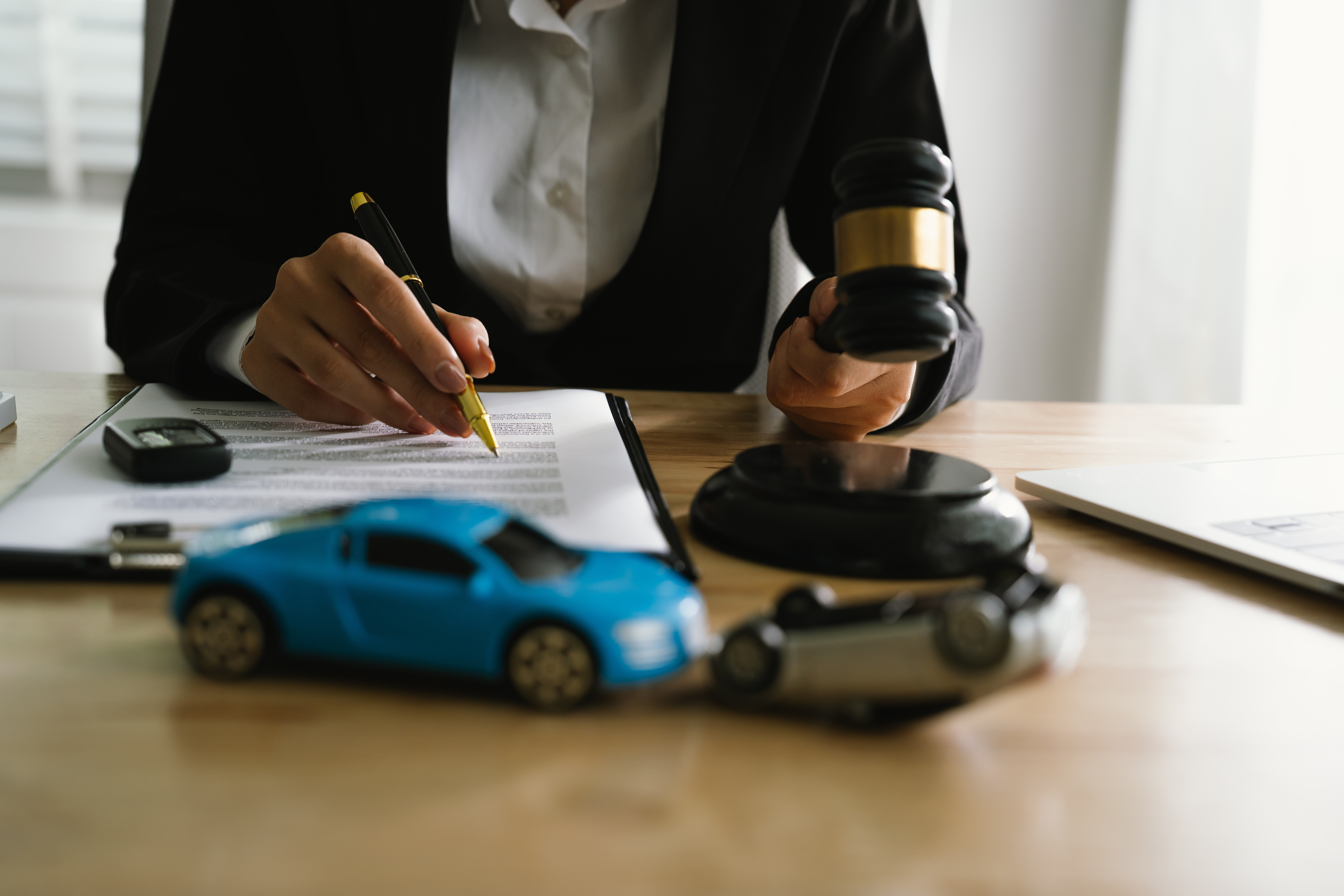 Attorney reviewing documents with gavel and toy cars representing an auto accident personal injury case.